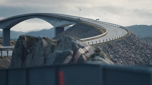 Storseisundet bridge on the Atlantic road rises above the turbulent waters. Heavy clouds in the sky.