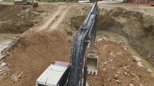Excavator Digging in Urban Construction Site Aerial