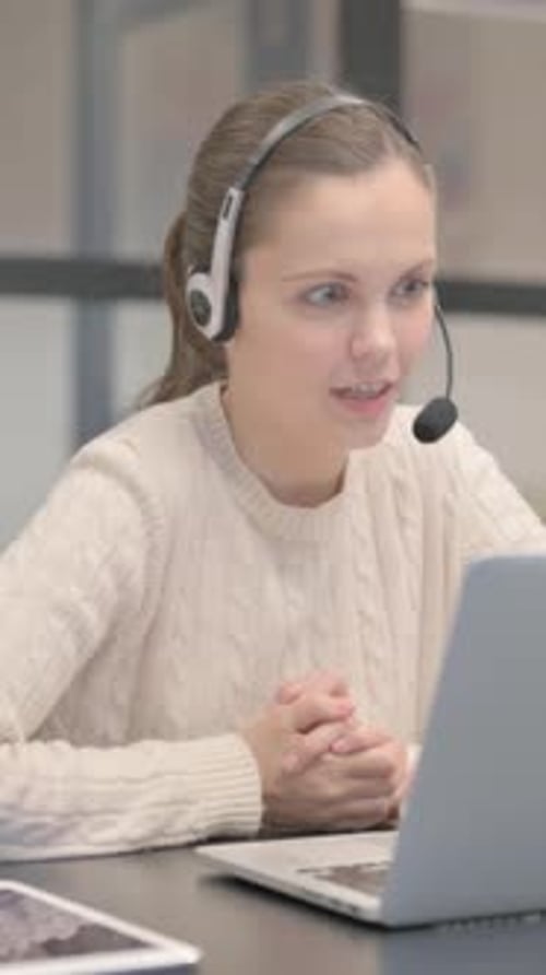 Woman Using Laptop with Headset in an Office