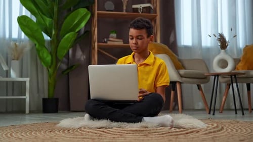 Boy Uses Laptop Sitting on a Rug