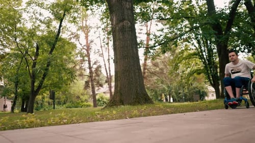 smiling happy man riding a wheelchair walking in a city park active lifestyle mobility obstacles