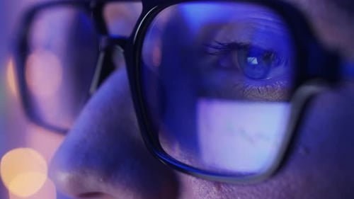 Man with glasses analyzing stock data at night