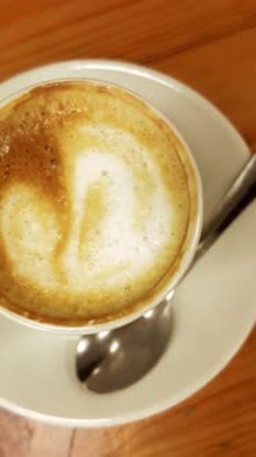 Cup of Cappuccino with Latte Art on a Wooden Table
