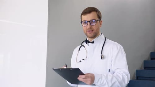 Lächelnder junger kaukasischer männlicher Arzt in weißer medizinischer Uniform zeigt guten Service im Krankenhaus