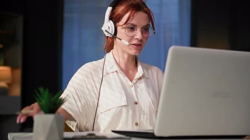 Call Center Operator Young Woman with a Microphone and Monitors Communicates Via Video Conference on