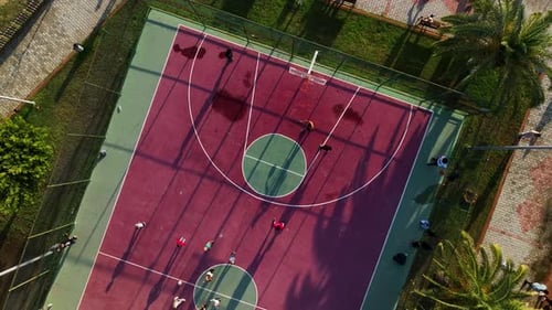 A Smooth Climb Up on a Drone From a Red Basketball Court People are Actively Playing Ball