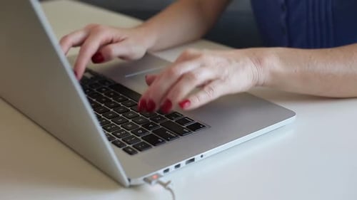 Frau mit rotem Nagellack tippt auf einem Laptop