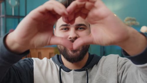 Man Makes Heart Shape with Hands and Smiles