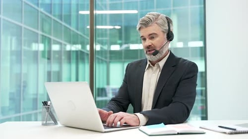 Man with Headset Works at Laptop in Modern Office