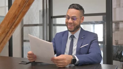 Excited Businessman Reads Documents in Office