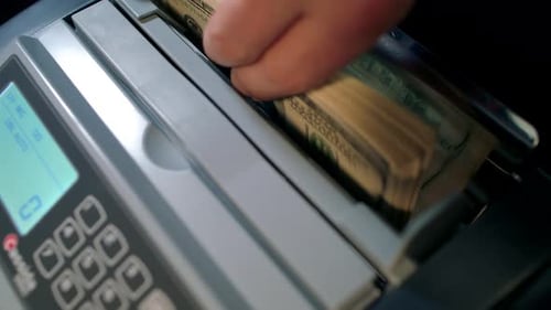 Currency counter counting US hundred dollar bills