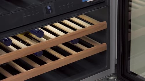 Un sommelier saca el estante para vinos del enfriador de vinos