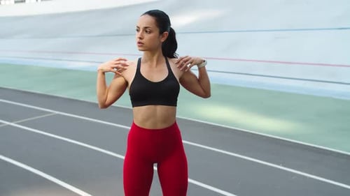 Sexy woman stretching arms outdoors preparing for workout at sport stadium