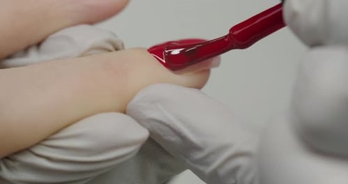Applying Red Nail Polish on Fingernail Close Up