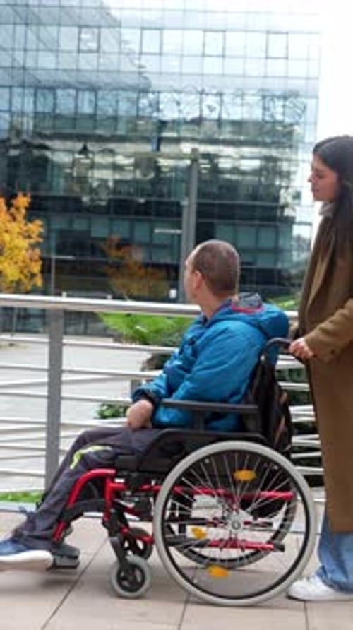 Teen boy in wheelchair with woman pushing him