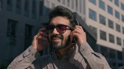 Carefree Arabian Indian Man in Sunglasses Wear Headphones Listen Music in Sunny City Joyful Happy