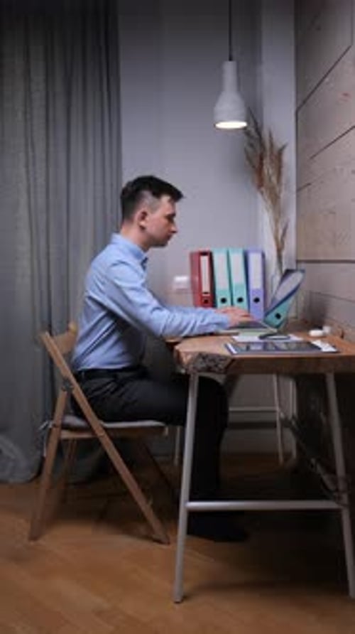 Young Man Works on Laptop at Desk Indoors