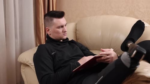 Man Relaxing Indoors, Reading a Book