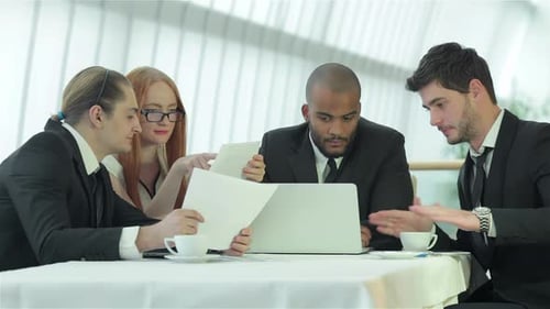 Four Smiling Successful Businessmen Sitting at Table in Office