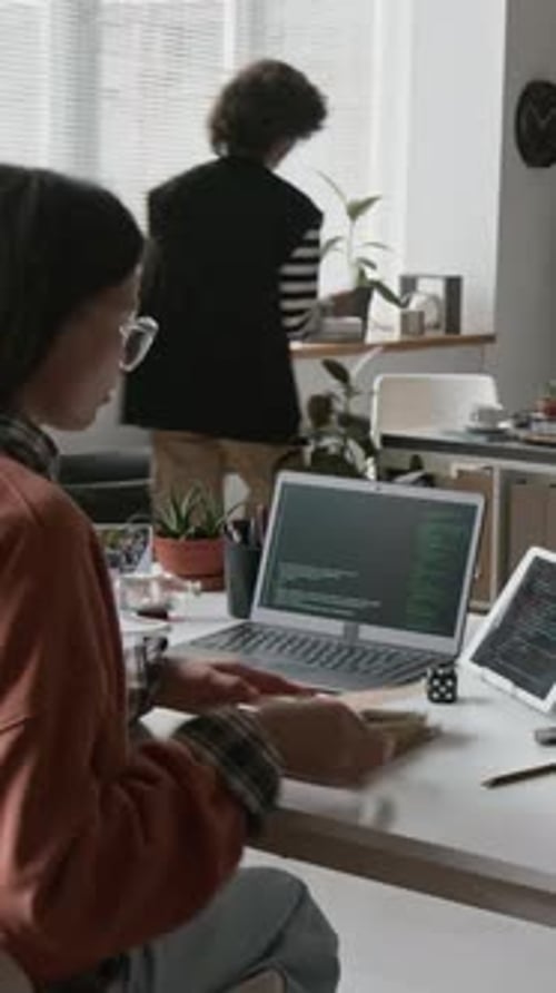 Female Programmer Coding on Laptop and Tablet at Busy IT Startup