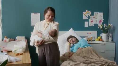 Grandma Rocking Baby in Arms in Maternity Hospital Room