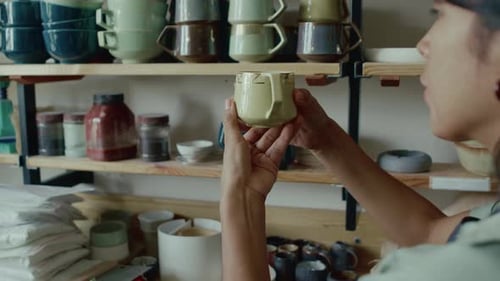 Artist Inspects Pottery Mug in Workshop