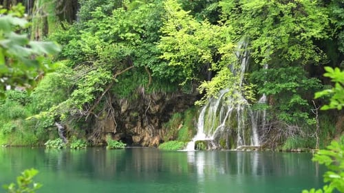 Versteckter Waldwasserfall, der in einen noch dunkelgrünen Teich stürzt