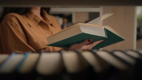 Closeup Unrecognizable Woman Reading Book in Library Female Student Teacher Standing Near Bookshelf