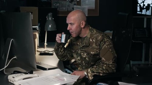 Military Analyst Doing Report on Computer at Desk in Office