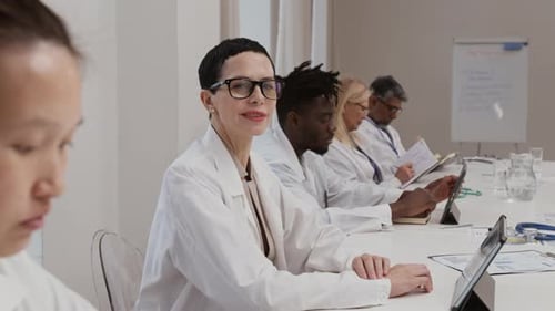 Medical Professionals in Meeting Room with Tablets and Documents