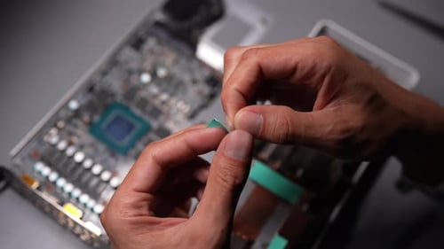 Top View of Technician Male Carefully Positioning a New Thermal Pad on a Graphics Card Ensuring