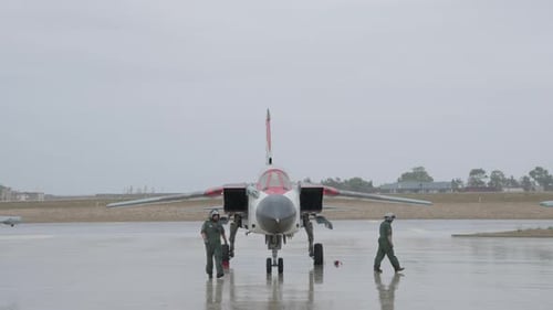 Aircraft Technicians Inspect Jet Fighter on Wet Tarmac