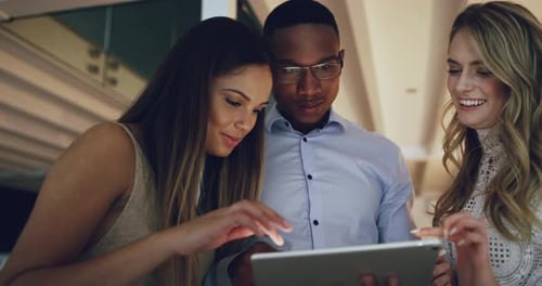 4k video footage of businesspeople using a tablet together while working late in the office