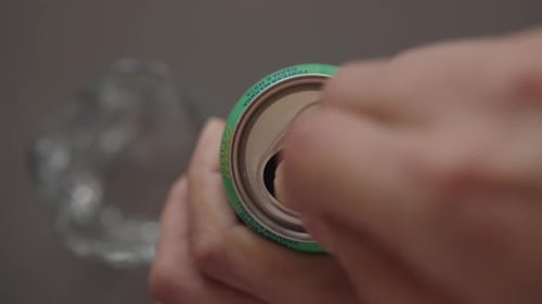 Top View of Male Hand Opening Aluminum Beverage Can Pulling Silver Tab to Break Seal and Access Cold