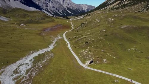 following bikers in a high mountain valley road with rocky summits on the background