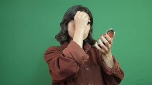 Woman Applies Mascara While Using Handheld Mirror