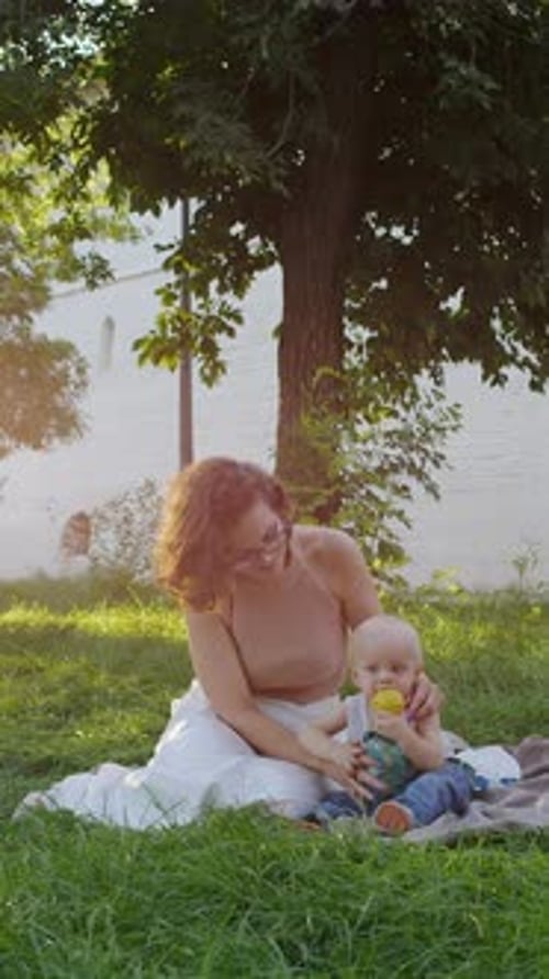Baby Drinking From Bottle Sitting on Blanket in Park
