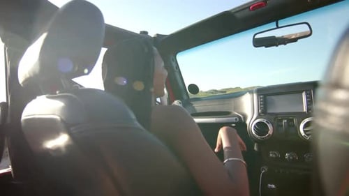 Young African American woman drives a convertible on a sunny day on a road trip