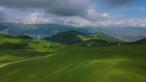 Enjoy the Breathtaking View of Lush Green Hills and Majestic Mountains Under Dramatic Clouds