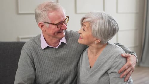 Senior Couple Embracing Affectionately on Gray Couch