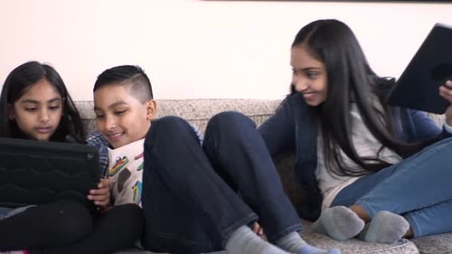 Children and Teen Enjoying Tablets Together on Couch