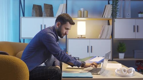 Young Man Working on Laptop in Home Office
