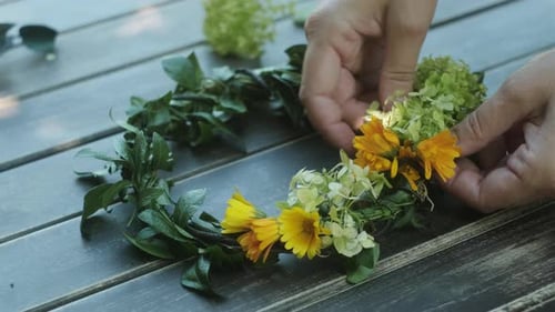 Hands Crafting Floral Wreath with Yellow and White Flowers