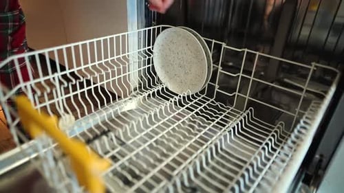 Loading the dishwasher after a meal. Close up.