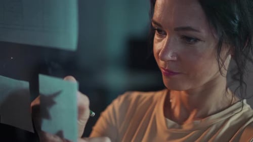 A Focused and Dedicated Professional Analyzing Sticky Notes in a Modern Collaborative Workspace