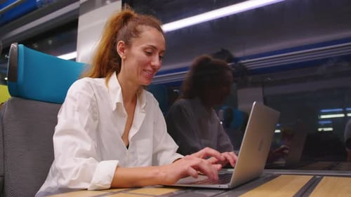Woman Working on Laptop in Modern Passenger Train
