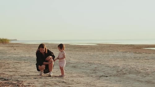 A Mother and Her Young Child Joyfully Playing Together on the Beach During a Beautiful Sunset