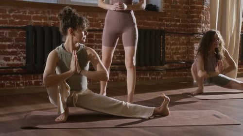 Female Yoga Teacher Correcting Women Performing Namaskarasana in Class