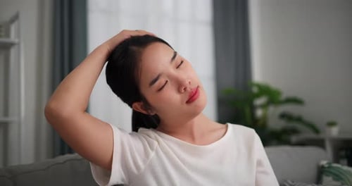 Woman Stretches Neck Muscles for Pain Relief Indoors