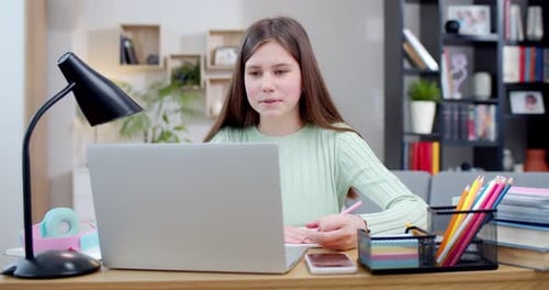 Pretty Caucasian Teen Girl Sitting at Laptop Videochatting and Having Online Class School By